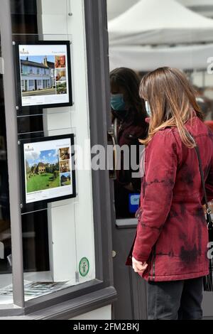 Frau mit Schutzmaske während der COVID-19-Pandemie beim Durchsehen von Immobilienmaklern in Immobilien, Alresford, Hampshire, Großbritannien. 03.05.2021. Stockfoto