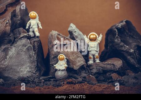 Astronaut mit goldenem Visier und weißem Raumanuit auf Felsoberfläche mit Weltraumhintergrund. Ein Astronaut auf dem Mond sitzt und meditiert, während ein anderer AS Stockfoto