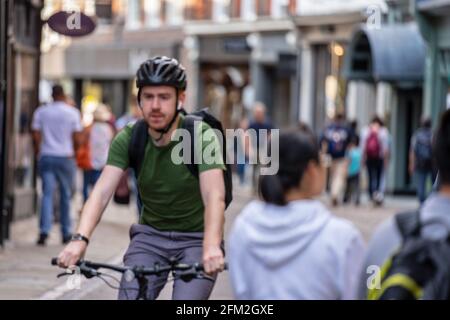 Ein Radfahrer mit Helm fährt entlang der Cambridge Street. Bewegungsunschärfe. Cambridge, Großbritannien, 1. August 2019. Stockfoto