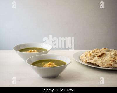 Molokhia (Juden Malge, Jute Malge, Malvenblätter) Einfache traditionelle ägyptische Suppe mit Kichererbsen und Fladenbrot Stockfoto