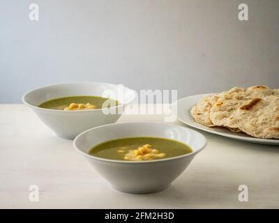 Molokhia (Juden Malge, Jute Malge, Malvenblätter) Einfache traditionelle ägyptische Suppe mit Kichererbsen und Fladenbrot Stockfoto