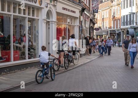 Familie auf Fahrrädern, die unter Fußgängern entlang der Cambridge Street fahren. Cambridge, Großbritannien, 1. August 2019. Stockfoto