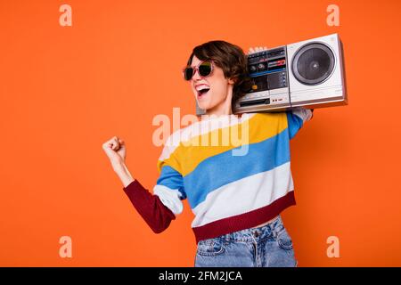 Foto von entzückten lustigen Mädchen Faust feiern suchen leeren Raum Halten Sie das Gestänge auf einem orangefarbenen Hintergrund isoliert Stockfoto