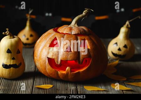 Halloween-Design mit Kürbissen. Schreckliches Symbol von Halloween - Jack-o-Laterne. Gruseliger Kürbiskopf mit Flamme und ein paar kleinen bemalten Kürbissen. Glowin Stockfoto