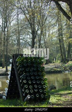 Vertikale Aufnahme von Glasflaschen am See umgeben von Bäume Stockfoto