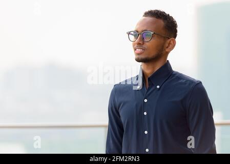 Porträt eines schönen afrikanischen Geschäftsmannes im Freien auf dem Dach in Bangkok, Thailand Stockfoto