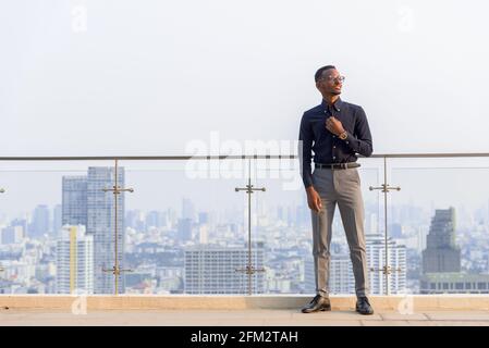 Porträt eines schönen afrikanischen Geschäftsmannes im Freien auf dem Dach in Bangkok, Thailand Stockfoto