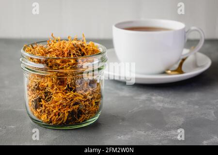 Kräutertee mit getrockneten Ringelblumen. Calendula-Tee in einer weißen Tasse. Stockfoto