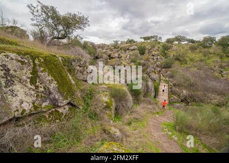 Kinder überqueren die Muelas-Brücke in der Nähe von Granithöhlen. Naturpark Cornalvo, Extremadura, Spanien Stockfoto