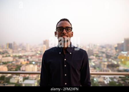 Porträt eines schönen afrikanischen Geschäftsmannes im Freien auf dem Dach in Bangkok, Thailand Stockfoto