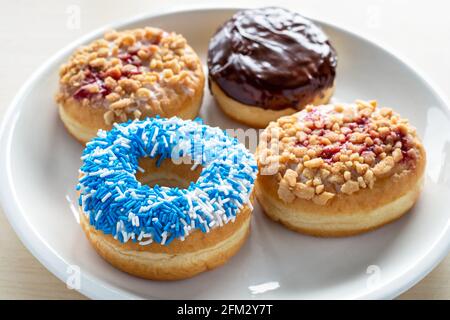 Donuts mit verschiedenen Belägen auf weißem Teller. Stockfoto