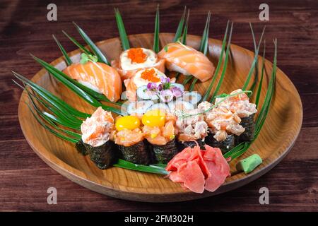 Sushi und Rollen mit rohen Wachteleiern auf einem Holzteller mit grünen Blättern. Holztisch. Selektiver Fokus Stockfoto