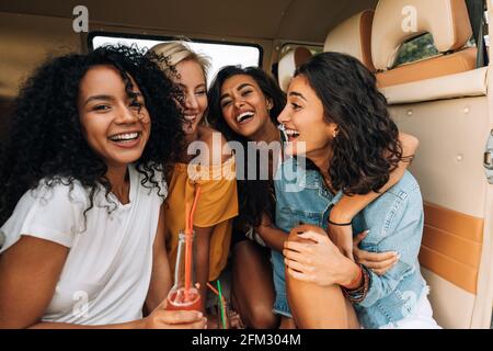 Multiethnische Gruppe junger Frauen, die lachen, während sie in einem sitzen minivan Stockfoto