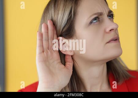 Frau hält ihre Hand nahe an ihr Ohr, um besser zu hören Stockfoto