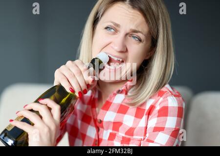 Frau öffnet Flasche Champagner mit ihren Zähnen. Stockfoto