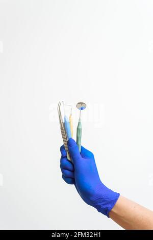 Die Hand des Zahnarztes in einem blauen Handschuh hält zahnärztliche Instrumente. Werbung für Zahnmedizin und zahnärztliche Dienstleistungen. Stockfoto