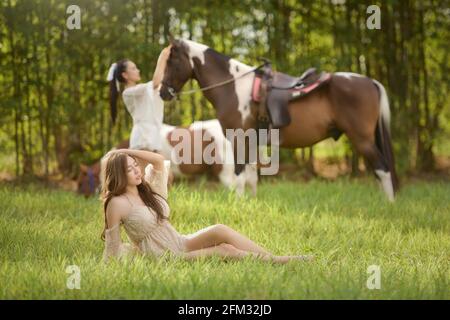 Zwei Frauen auf einer Wiese mit einem Pferd, Thailand Stockfoto