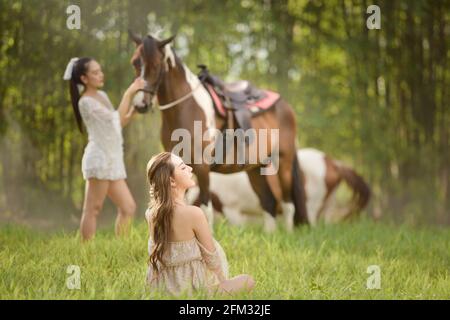 Zwei Frauen auf einer Wiese mit einem Pferd, Thailand Stockfoto