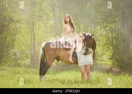 Zwei Frauen auf einer Wiese mit einem Pferd, Thailand Stockfoto
