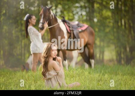 Zwei Frauen auf einer Wiese mit einem Pferd, Thailand Stockfoto