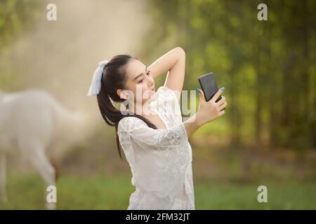 Schöne Frau, die auf einer Wiese steht und ein Selfie macht, Thailand Stockfoto