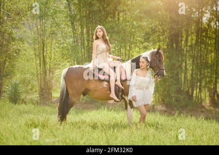 Zwei Frauen auf einer Wiese mit einem Pferd, Thailand Stockfoto