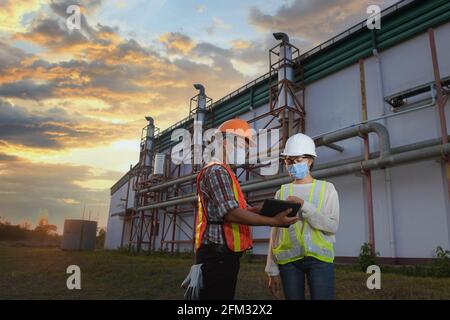 Zwei Ingenieure schauen sich Baupläne vor einer Fabrik in Thailand an Stockfoto