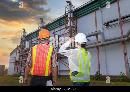 Zwei Ingenieure schauen sich Baupläne vor einer Fabrik in Thailand an Stockfoto