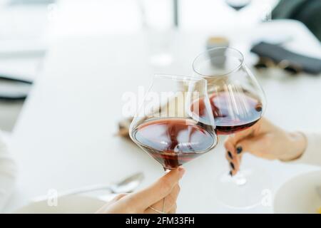 Zwei Frauen, die einen festlichen Toast mit Gläsern aus Rot machen Wein Stockfoto