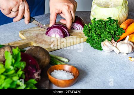 Frau, die eine rote Zwiebel aufschneiden und Gemüse zubereiten Stockfoto