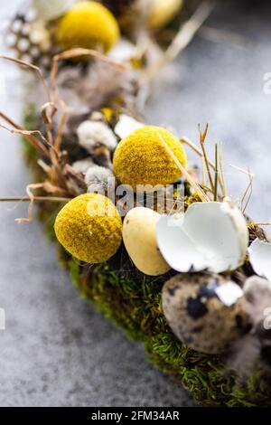 Nahaufnahme eines Osterkranzes mit Wachteleiern und Federn auf einem Tisch Stockfoto