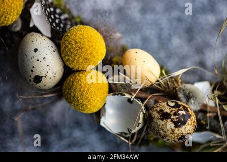 Nahaufnahme eines Osterkranzes mit Wachteleiern und Federn auf einem Tisch Stockfoto