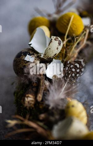 Nahaufnahme eines Osterkranzes mit Wachteleiern und Federn auf einem Tisch Stockfoto