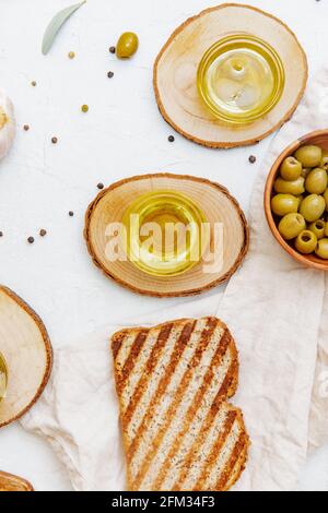 Blick von oben auf eine Scheibe Ciabatta Toast mit grünen Oliven, Olivenöl und frischem Knoblauch Stockfoto