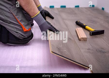 Männliche Hände legen Holzplatte aus Laminatboden im Raum. Selektiver Fokus. Stockfoto