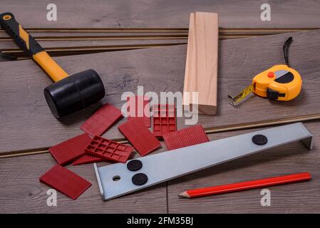 Planken von Laminatboden und Ausrüstung oder Werkzeuge, um sie zu installieren, Hammer, Brecheisen, Distanzstücke, Hammer und Meter. Selektiver Fokus. Stockfoto