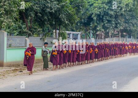 BAGAN, MYANMAR - 8. DEZEMBER 2016: Reihen buddhistischer Mönche mit Schalen, die ihre täglichen Almosen sammeln. Stockfoto