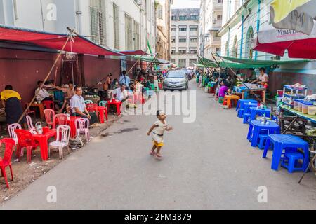 YANGON, MYANMAR - 15. DEZEMBER 2016: Enge Straße mit Imbissständen in Yangon. Stockfoto