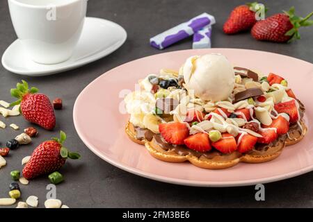 Herzwaffel mit Banane und Erdbeere mit Gummy Candy und Eis darauf. Stockfoto