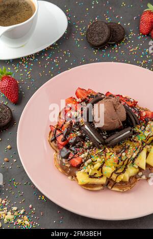 Herzwaffel mit Ananas und Erdbeere mit Gummy Candy und Eis darauf. Stockfoto