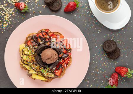 Herzwaffel mit Ananas und Erdbeere mit Gummy Candy und Eis darauf. Stockfoto