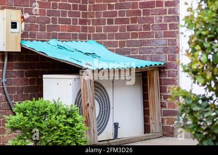 Eine Klimaanlage für den Außenbereich, die auf dem Boden in einem Garten in einem kleinen Schutzschuppen mit lackiertem Wellblechdach aufgestellt wird. Diese PR Stockfoto