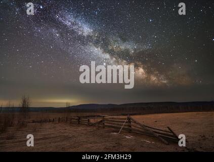 Sternenhimmel über dem Farmfeld. Kosmos Raum Natur Landschaft über trockenes Gras und Holzzaun. Sternbild bei Nacht. Universum, dunkel, Galaxie CO Stockfoto