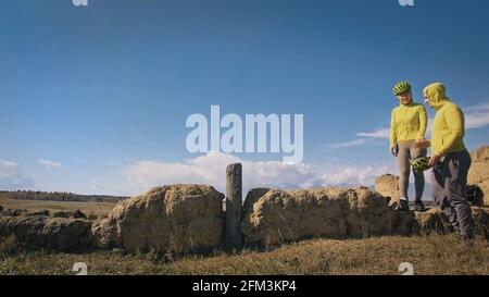 Der Mann und die Frau reisen auf gemischtem Terrain mit Bikepacking. Die beiden Personen reisen mit Fahrradtaschen. Schneebedeckte Berge. Stockfoto