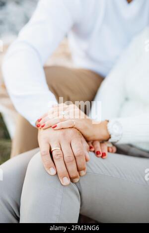 Die Hand der Frau verdeckte die Hand des Mannes. Die Hand des Mannes liegt auf dem Bein der Frau. Nahaufnahme Stockfoto