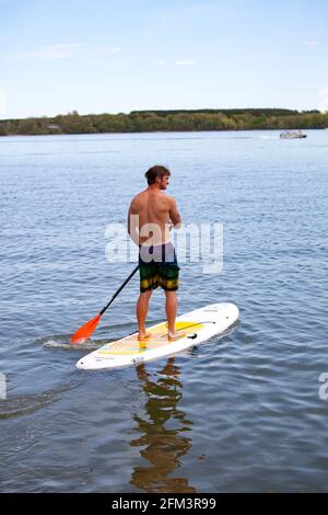 Teen genießt es, sein Paddelbrett auf einem ruhigen Clitherall Lake zu paddeln. Clitherall Minnesota, USA Stockfoto