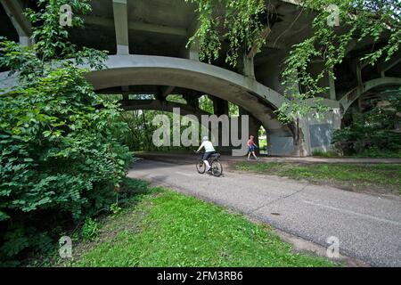 Fahrradfahrer und Spaziergänger fahren unter dem Bogen der Nicollet Avenue Bridge entlang des Minnehaha Parkway Regional Trail. Minneapolis Minnesota, USA Stockfoto