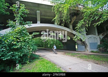 Fahrradfahrer, der den Minnehaha Parkway Regional Trail entlang fährt und unter dem Bogen der Nicollet Avenue Bridge verläuft. Minneapolis Minnesota, USA Stockfoto