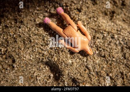 Verlassene kopflose Childs Puppe in einem Sandkasten, South Island, Neuseeland Stockfoto