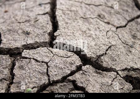 Tiefe Risse im Boden. Der trockene Boden rissig. Schwarzer Boden mit tiefen Spaltungen. Die Folgen eines Erdbebens. Stockfoto